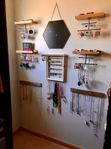 Jewelry display on a wall. Includes shelves, necklace racks, and a hexagonal mirror.