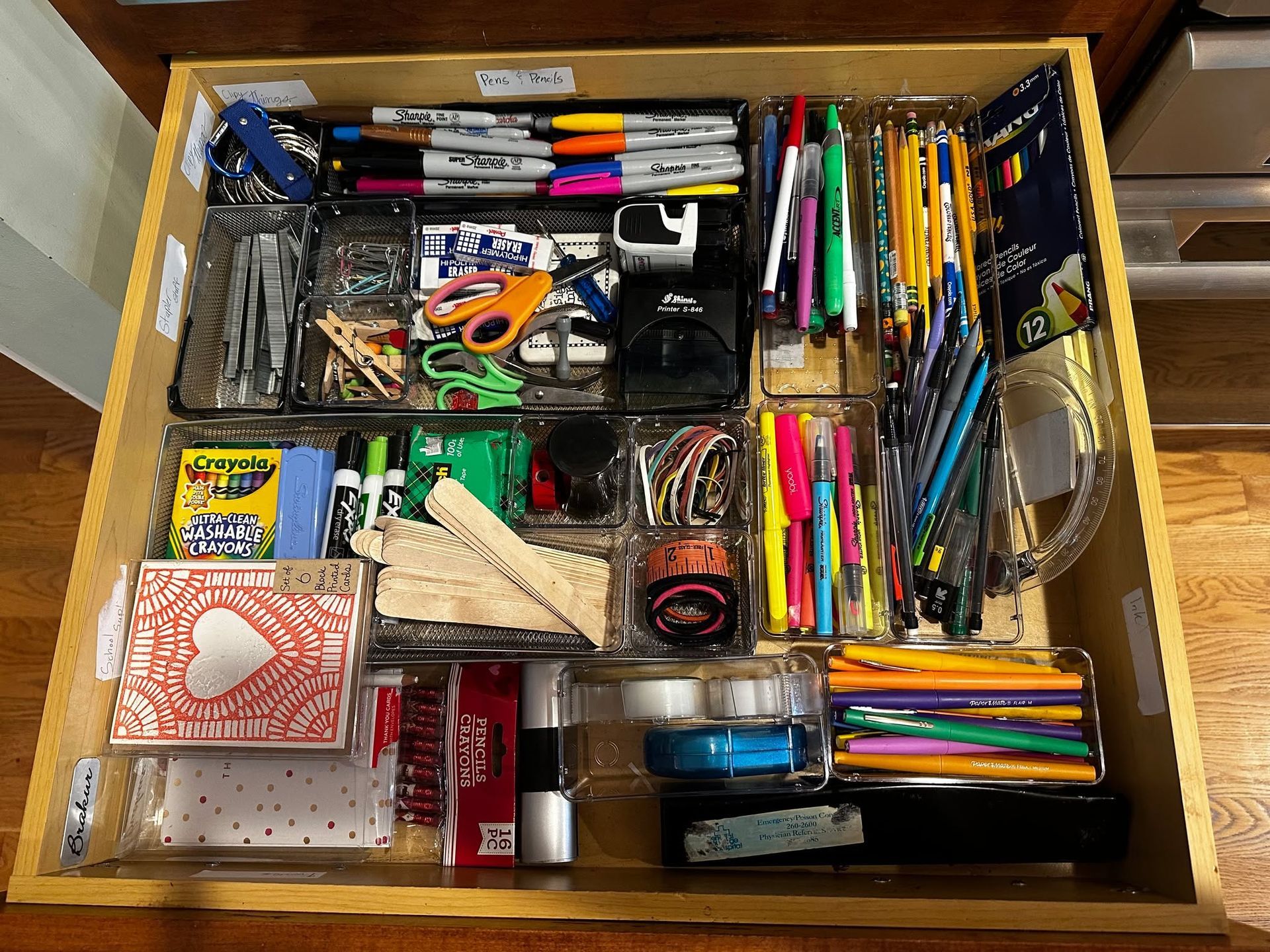 Open drawer filled with various organized art supplies, including markers, pens, and scissors.