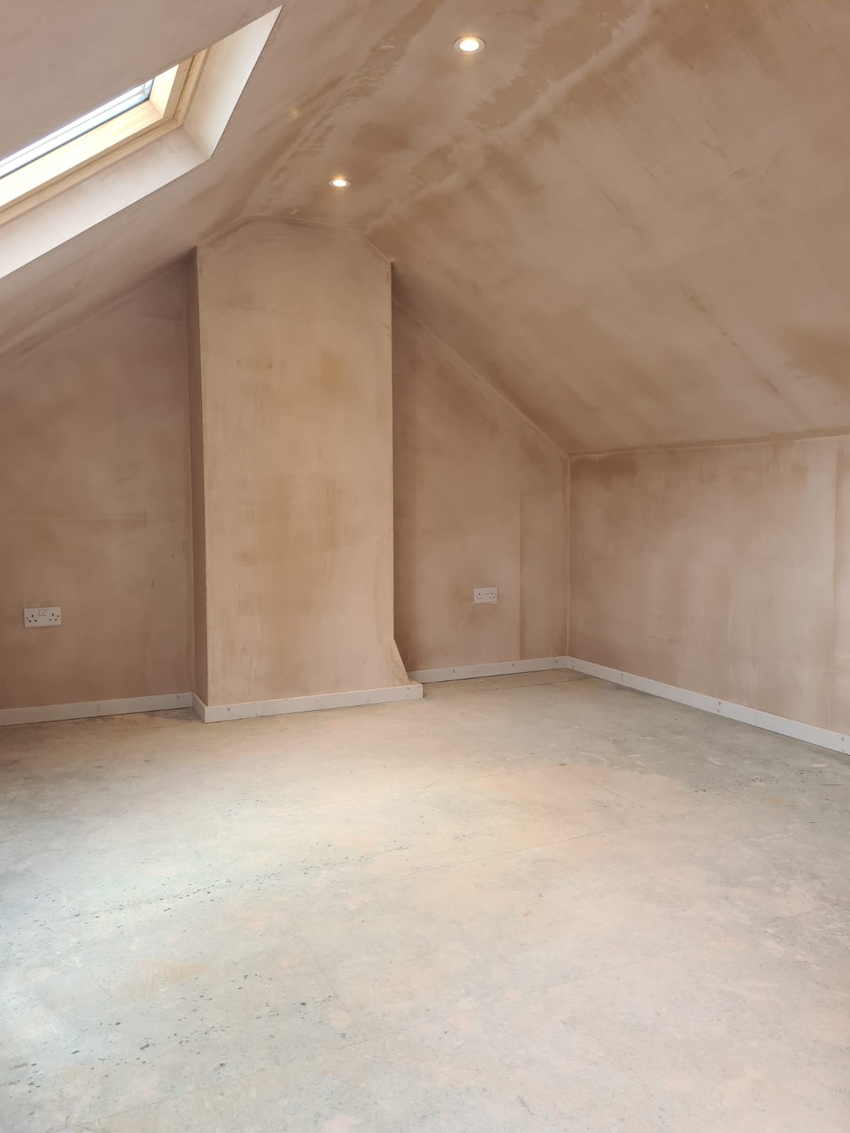 An empty room with a slanted ceiling and a skylight.