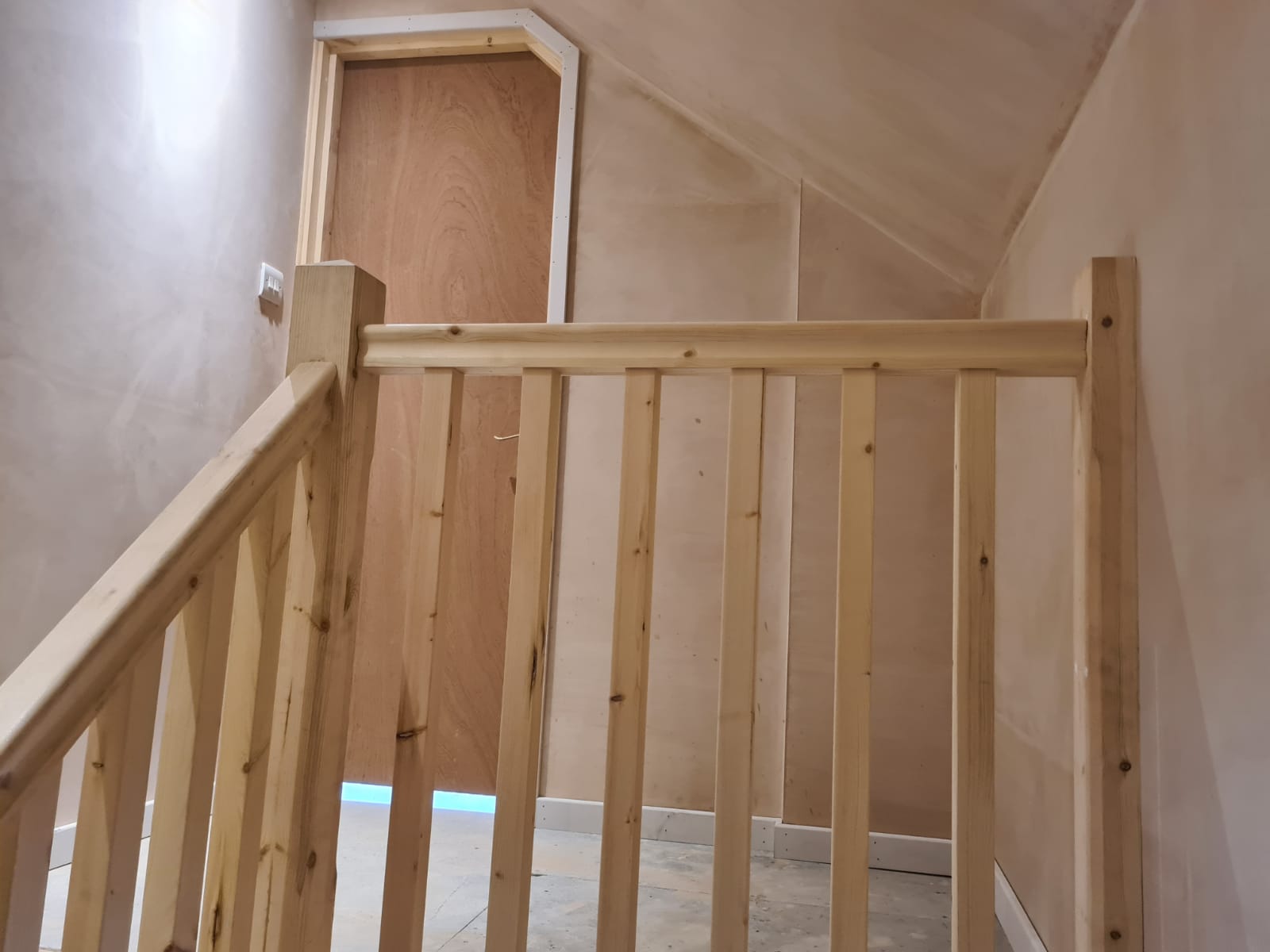 A wooden railing on a staircase with a door in the background.