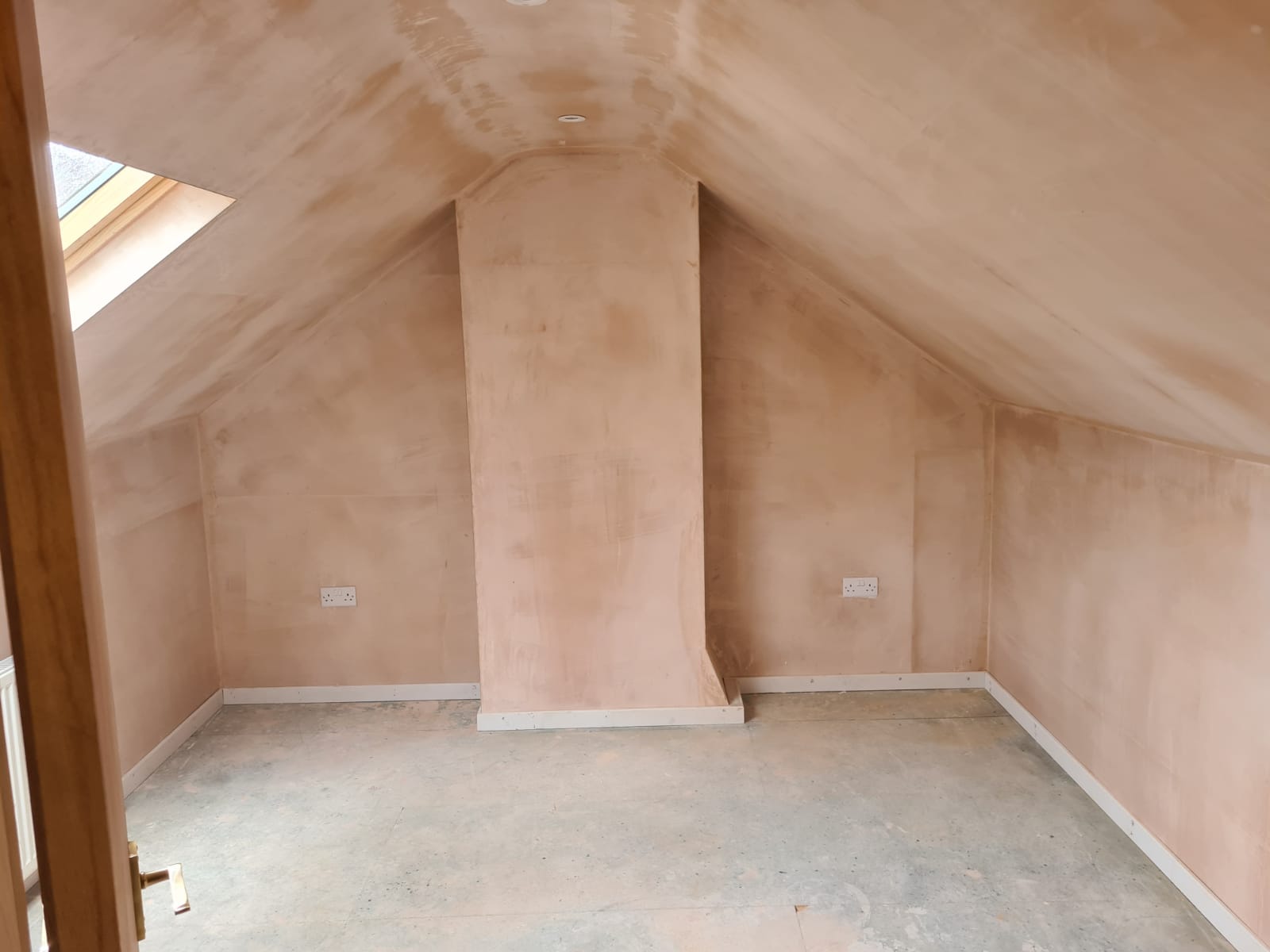 An empty attic with a skylight and a chimney.