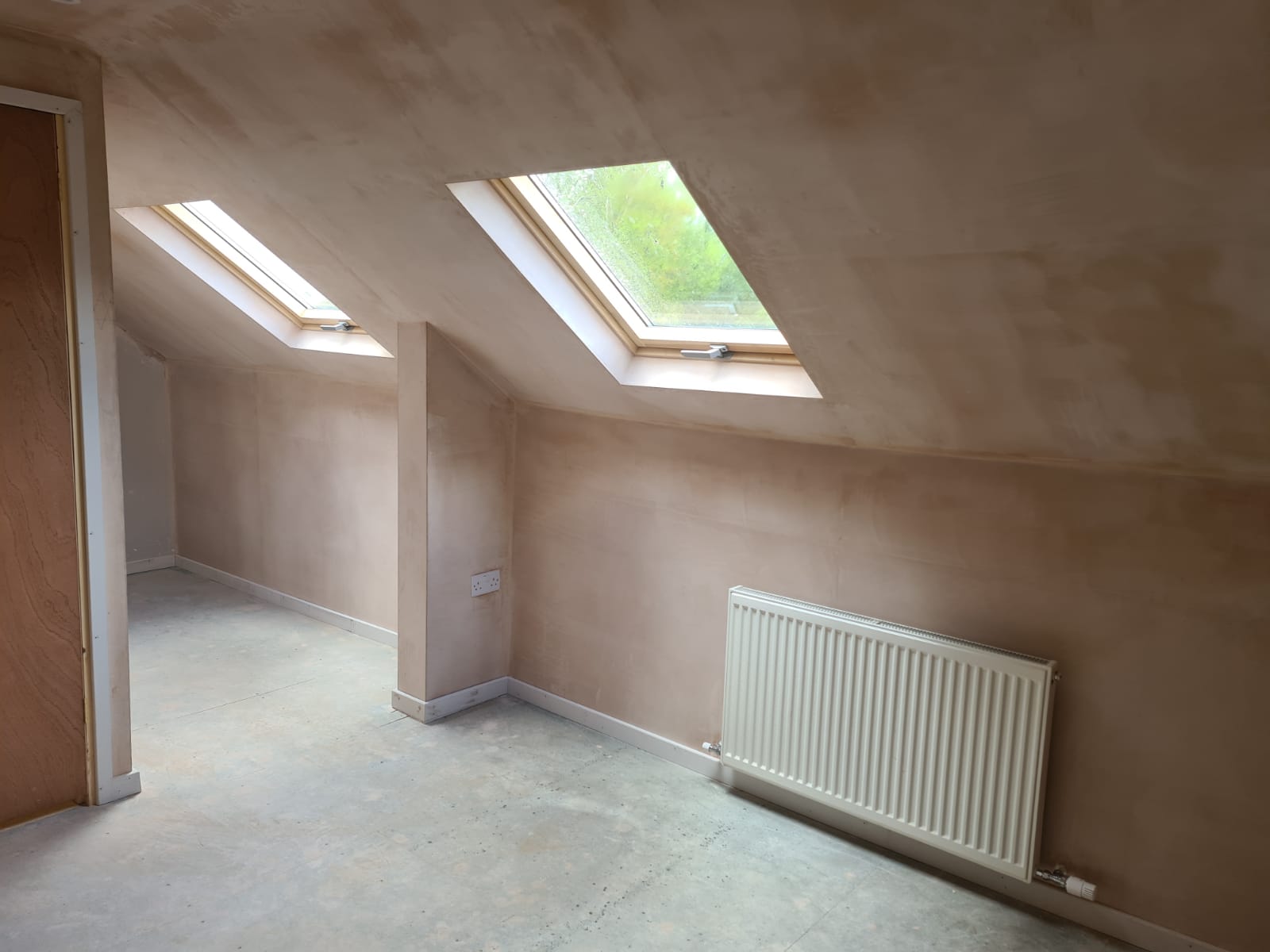 An empty room with two skylights and a radiator.