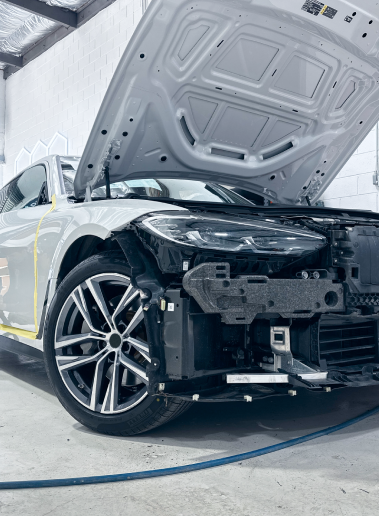 Silver car with open hood, front end disassembled in a repair shop. | Ma's Auto Body
