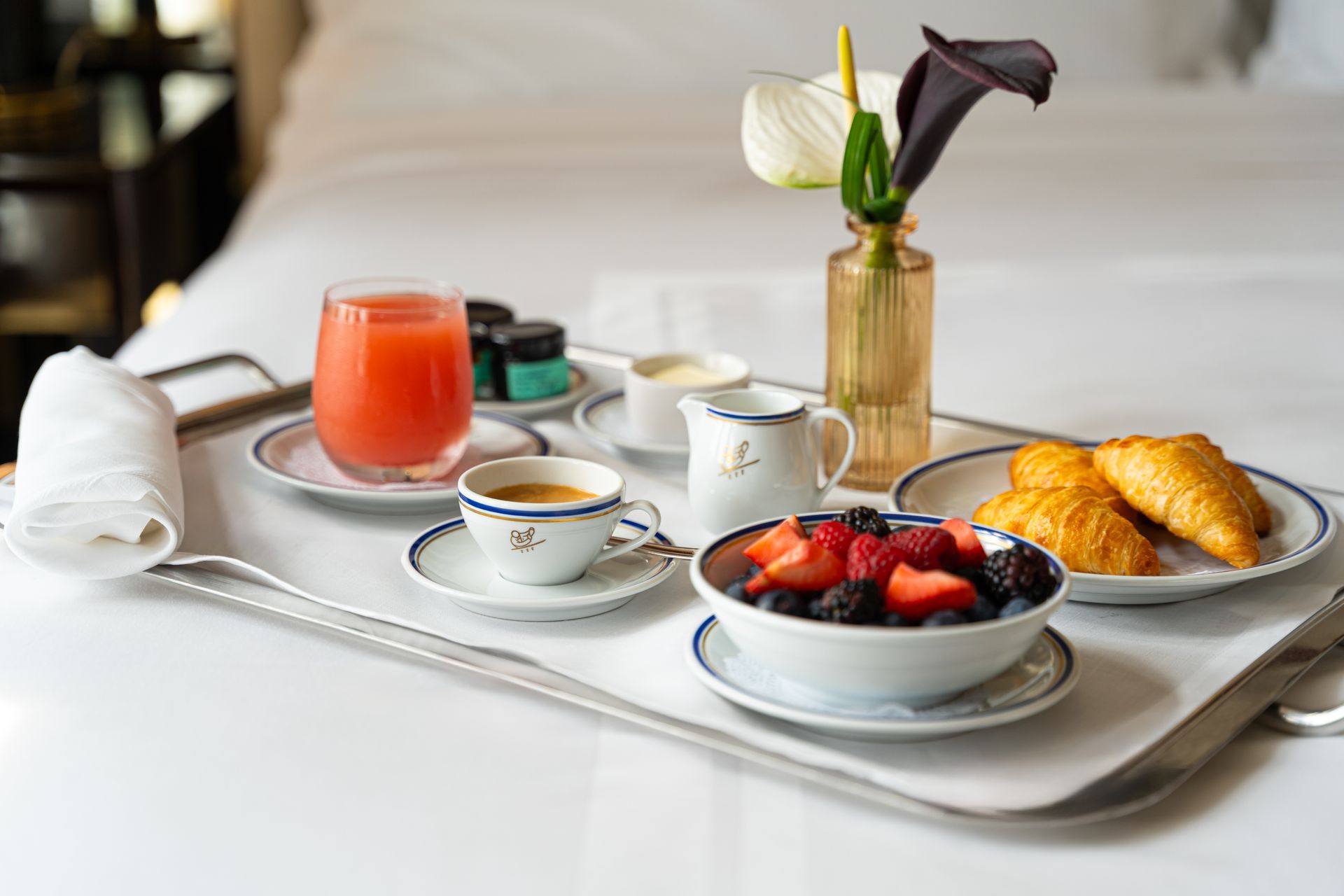 A tray of breakfast in a hotel room on a bed.