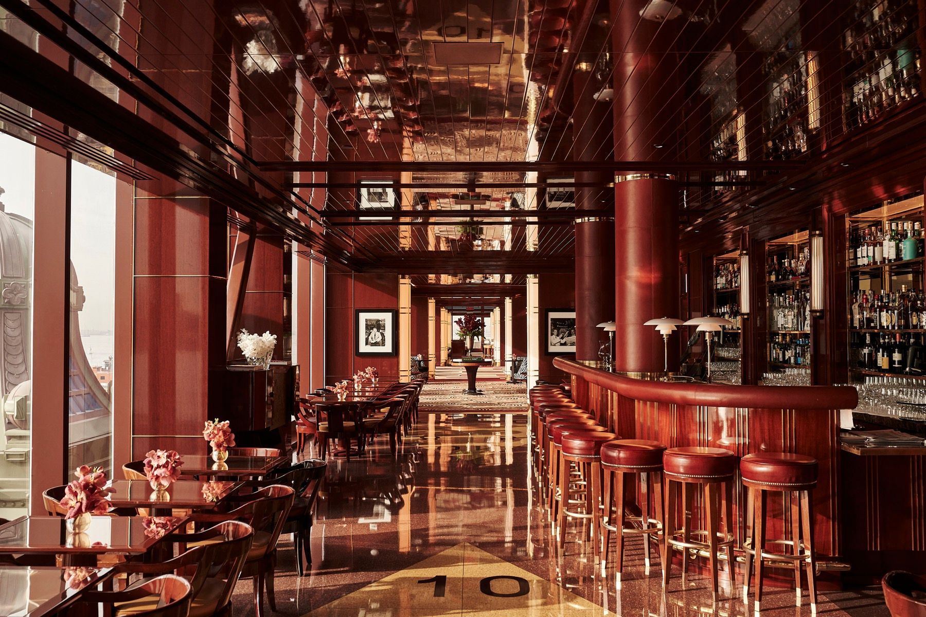 A restaurant with tables and chairs and a bar with the letter t on the floor