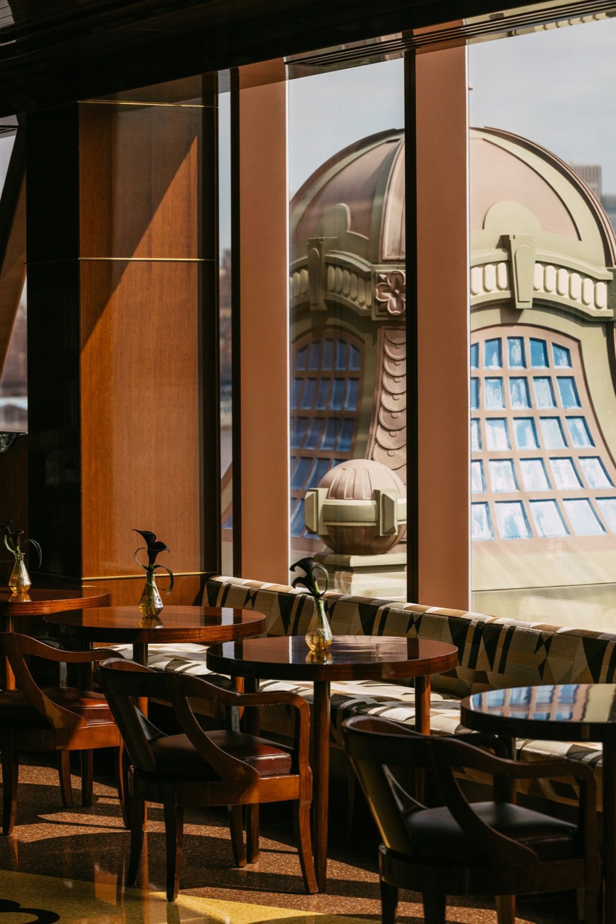 A restaurant with tables and chairs and a large window with a view of a building.