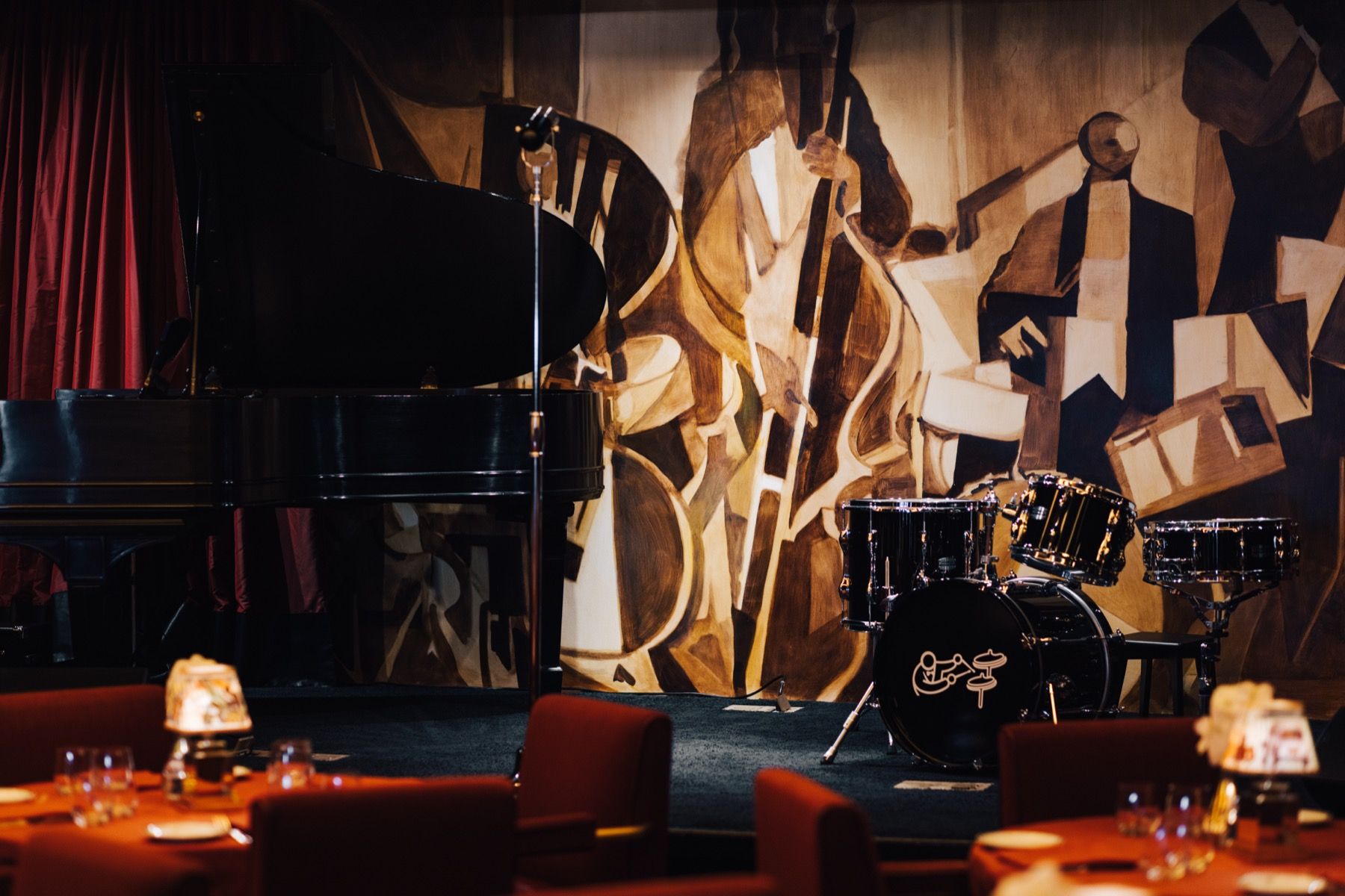 A large dining room with tables and chairs and a vase of flowers in the middle.