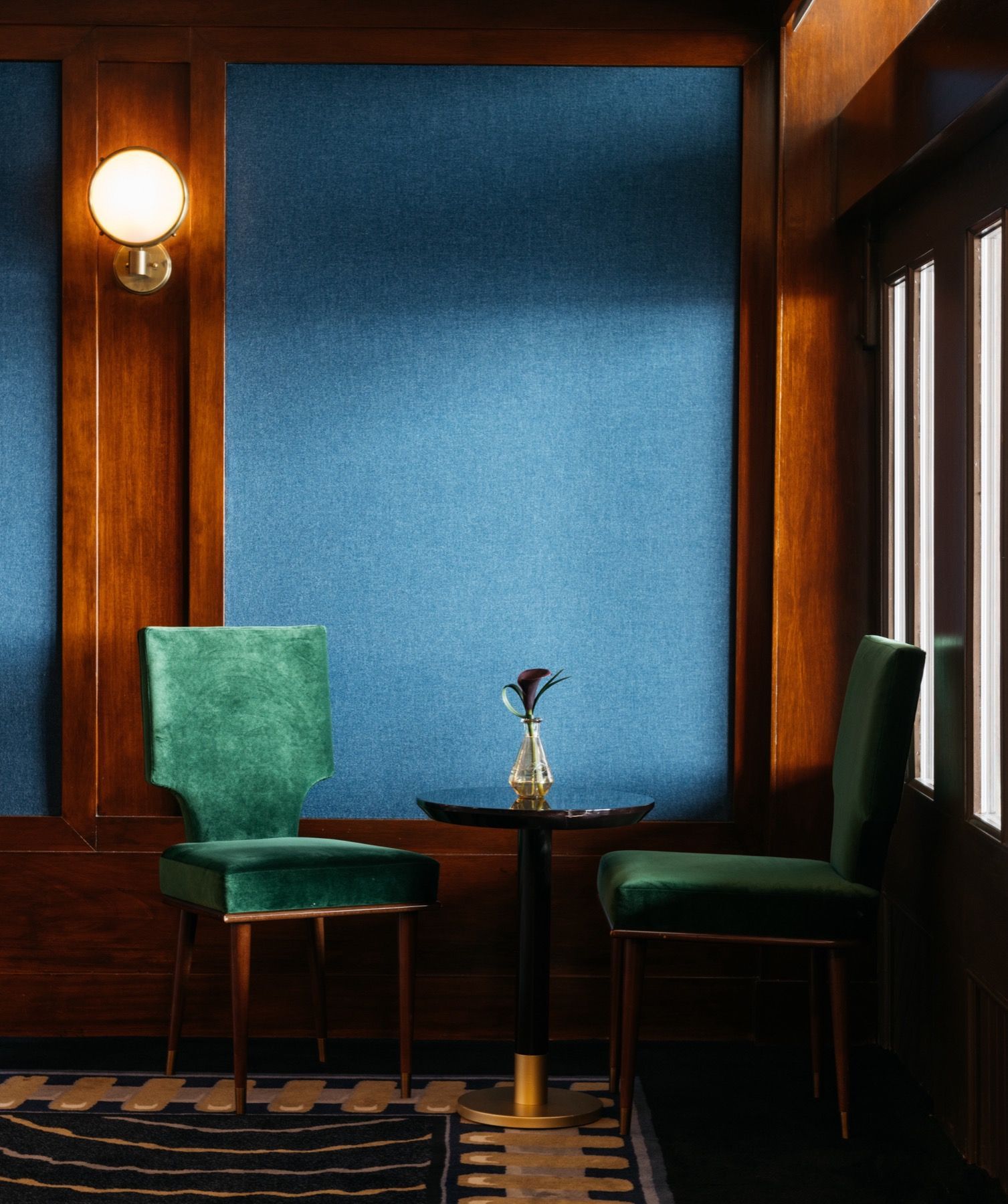 A room with two chairs and a table with a vase of flowers on it