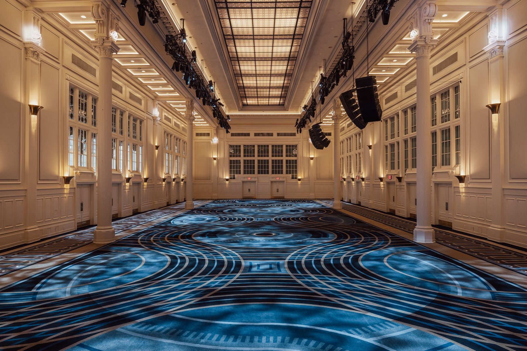 A large empty room with a blue carpet and a ceiling light.