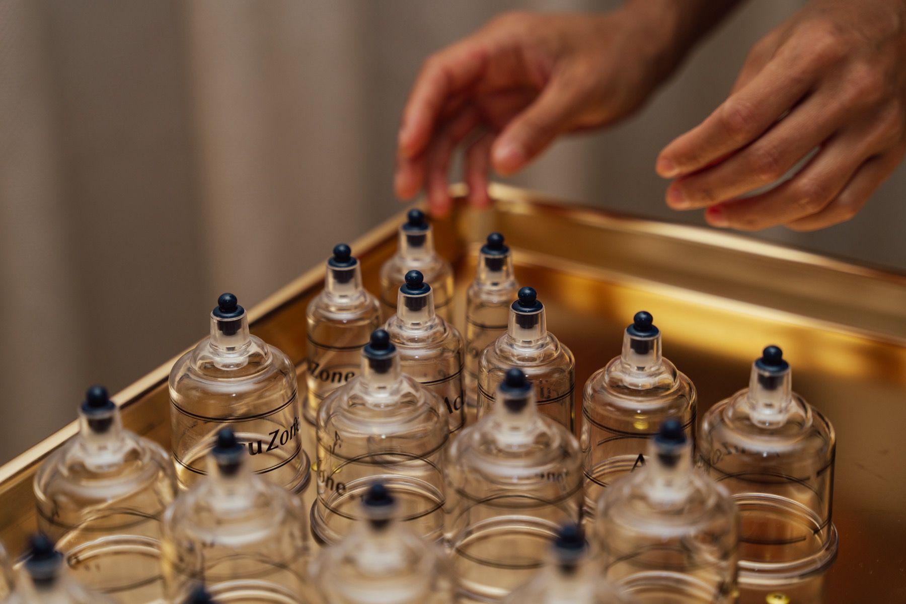 A person is putting a needle into a glass cup on a tray.