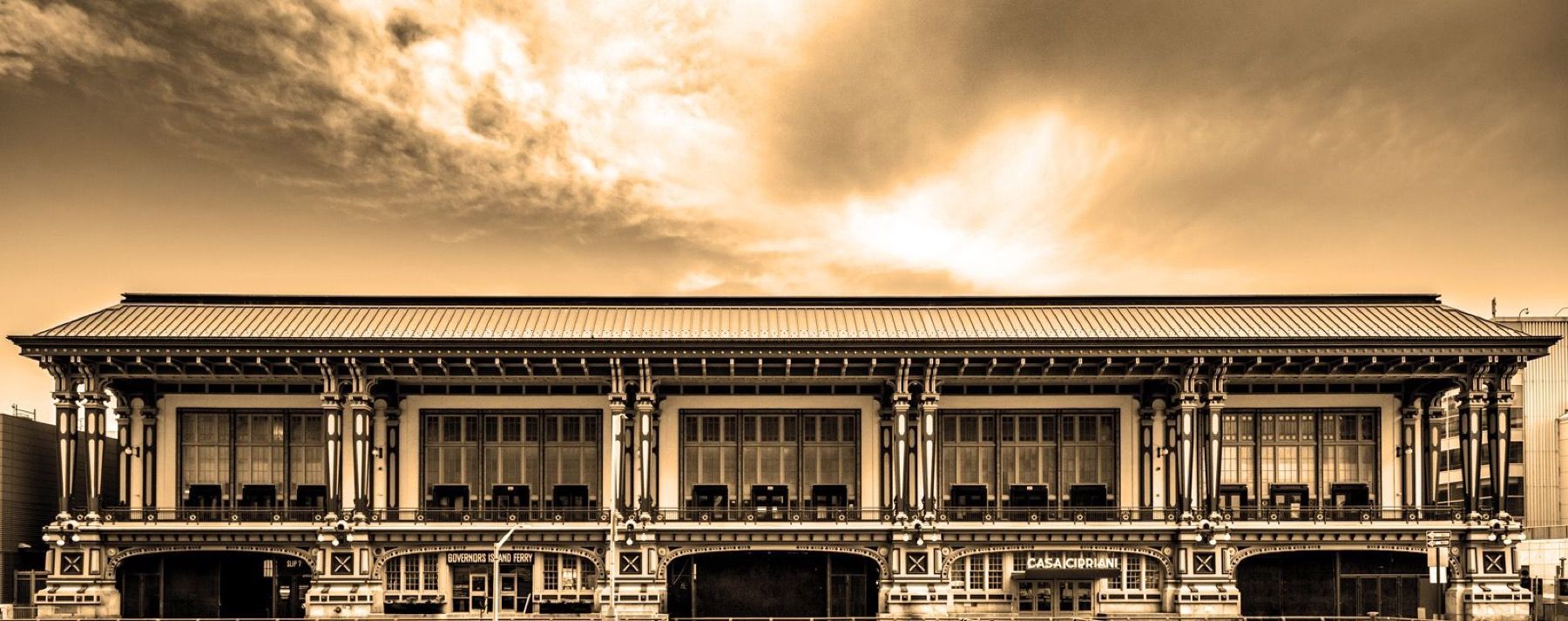 A black and white photo of a large building with a cloudy sky in the background.