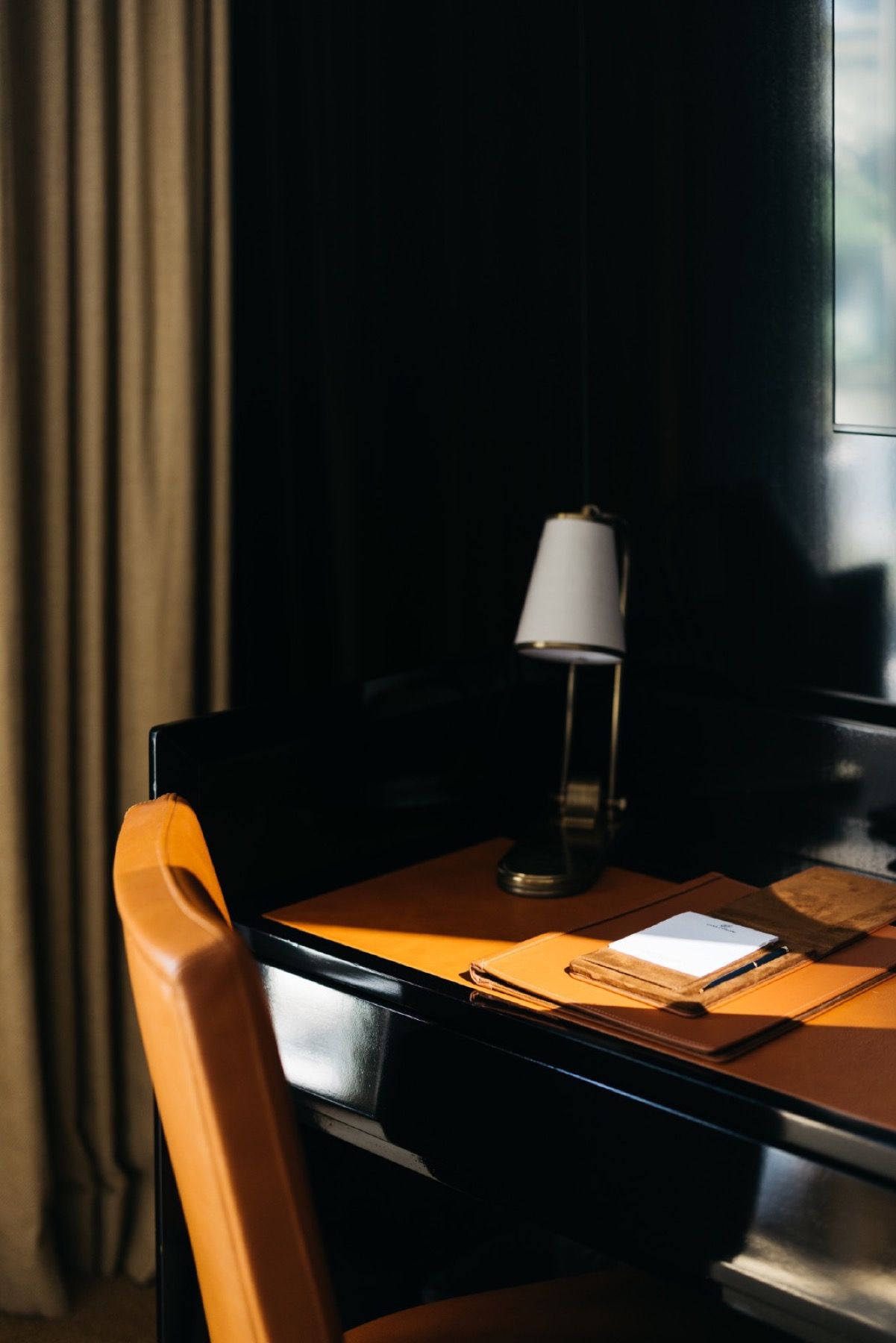 A desk with a lamp and a chair in a dark room.