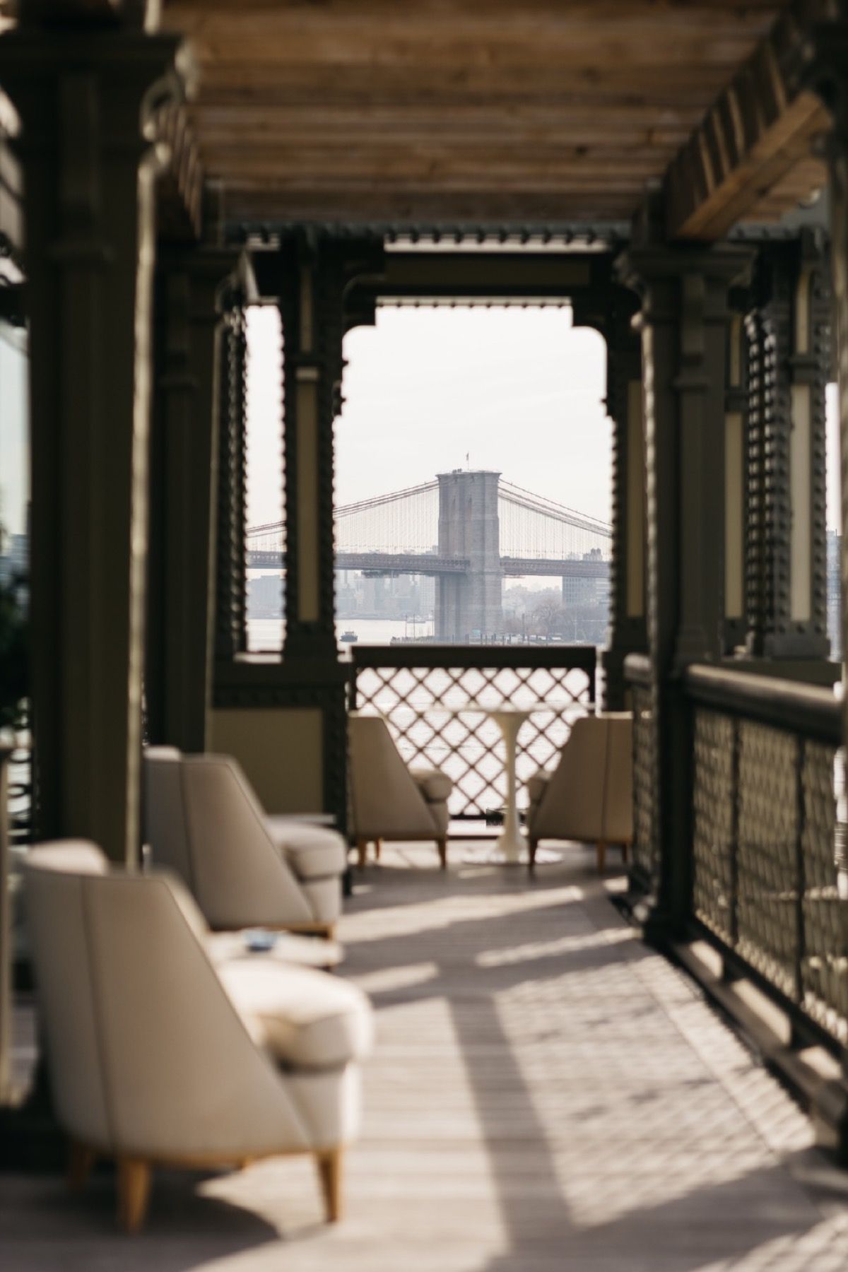 A balcony with chairs and a table with a view of a bridge
