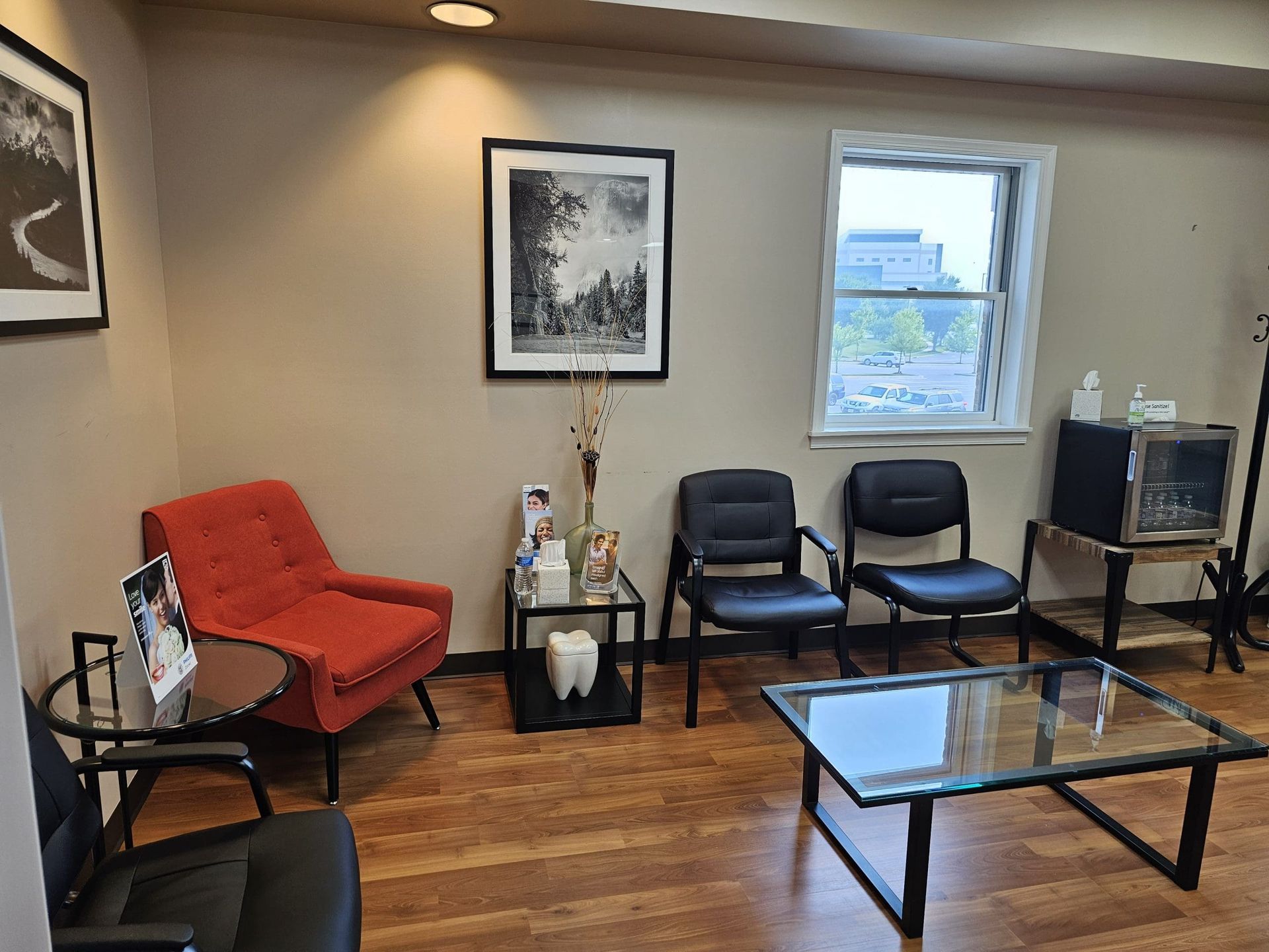 A waiting room with a couch , chairs , a coffee table and a window.