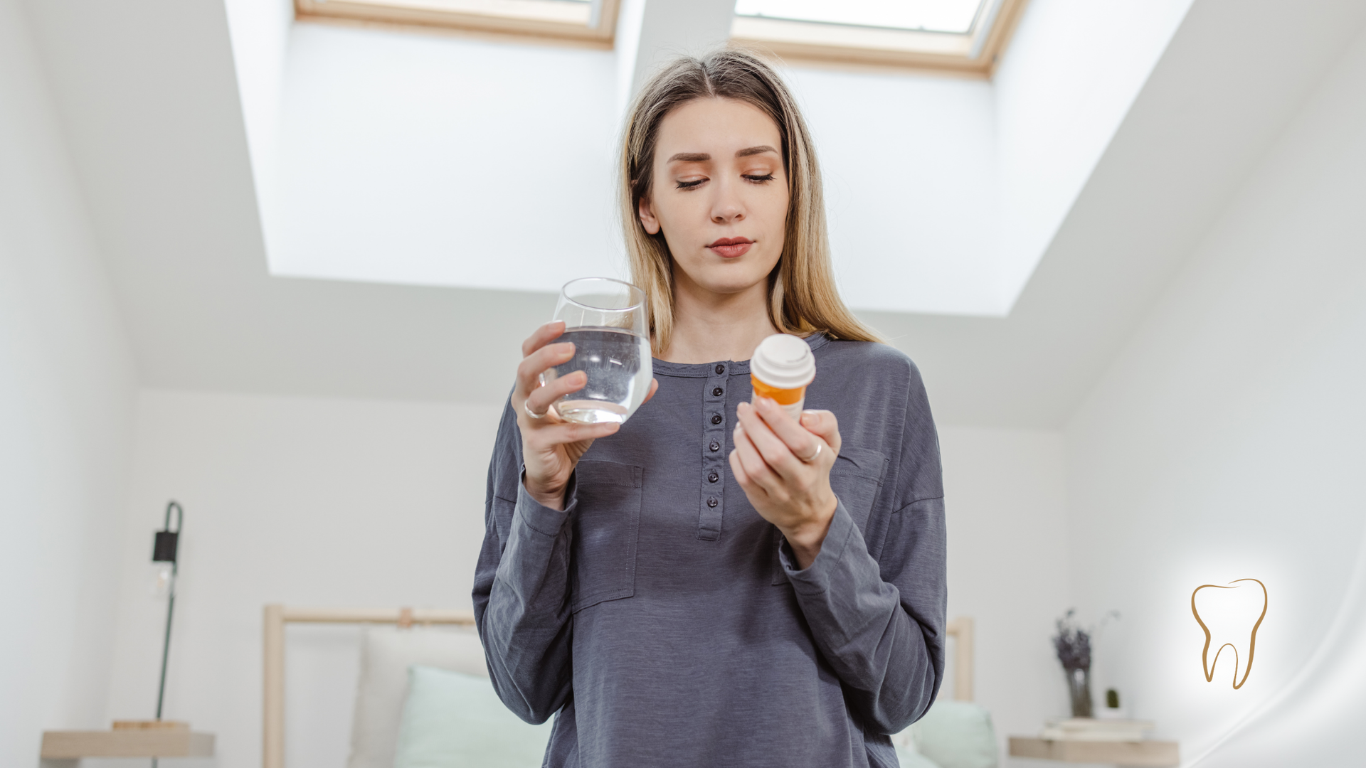 A woman is holding a bottle of pills and a glass of water.