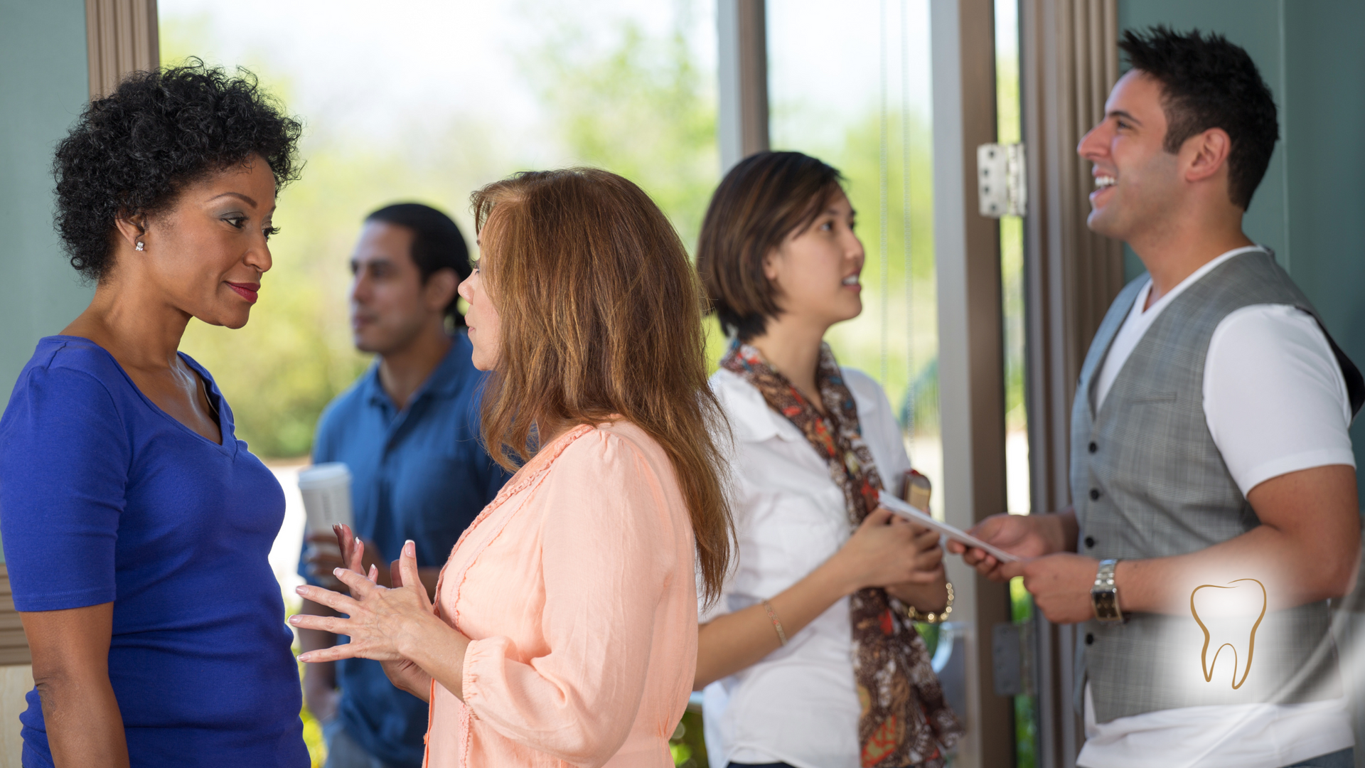 A group of people are standing in a room talking to each other.