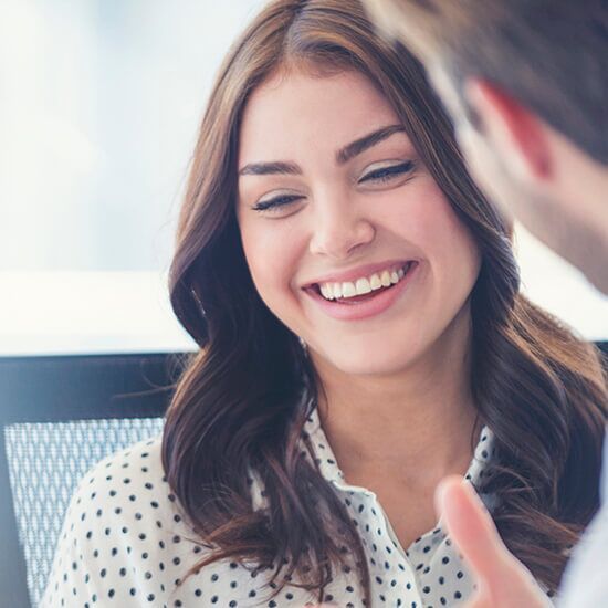 A woman in a polka dot shirt is smiling while talking to a man