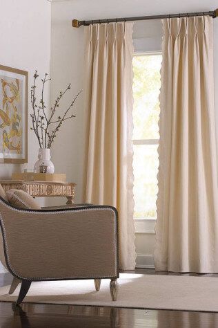 A living room with a chair , table , and curtains.