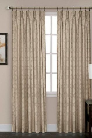 A pair of beige curtains are hanging on a window in a living room.
