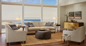 A living room with a couch , chairs , ottoman and large windows.