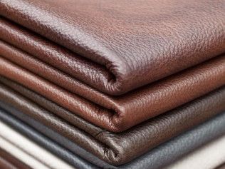 A close up of a stack of brown and black leather sheets.
