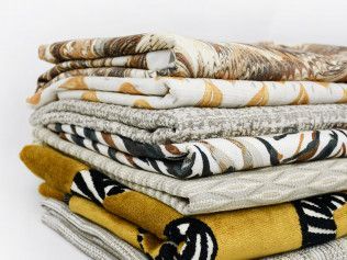 A pile of blankets are stacked on top of each other on a white surface.