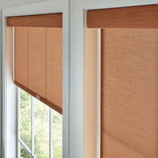 A pair of roller shades on a window in a room.