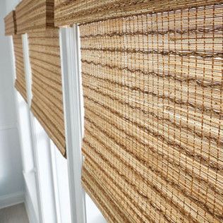 A row of bamboo blinds are hanging on a window.