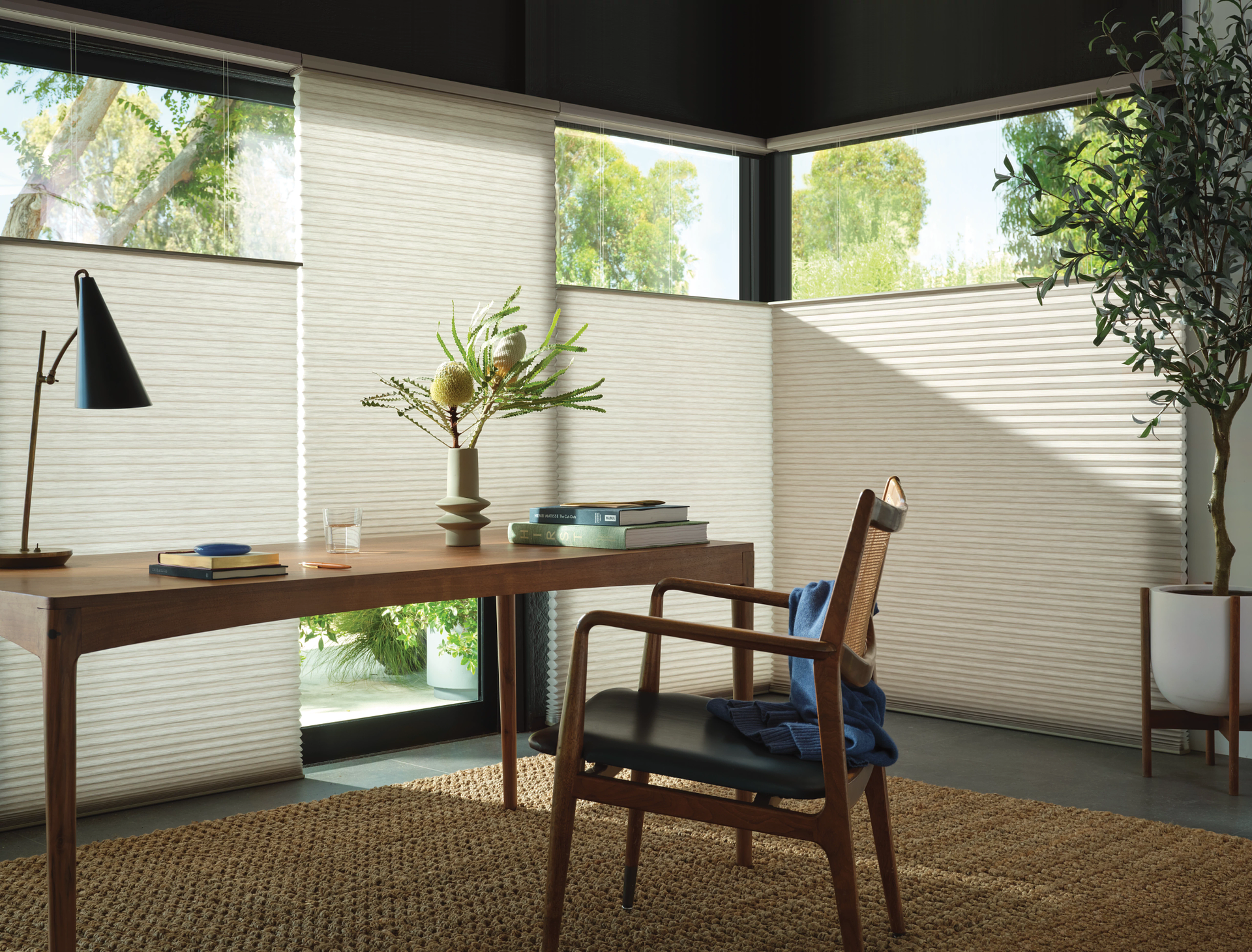 A home office with a desk , chair , lamp and window.