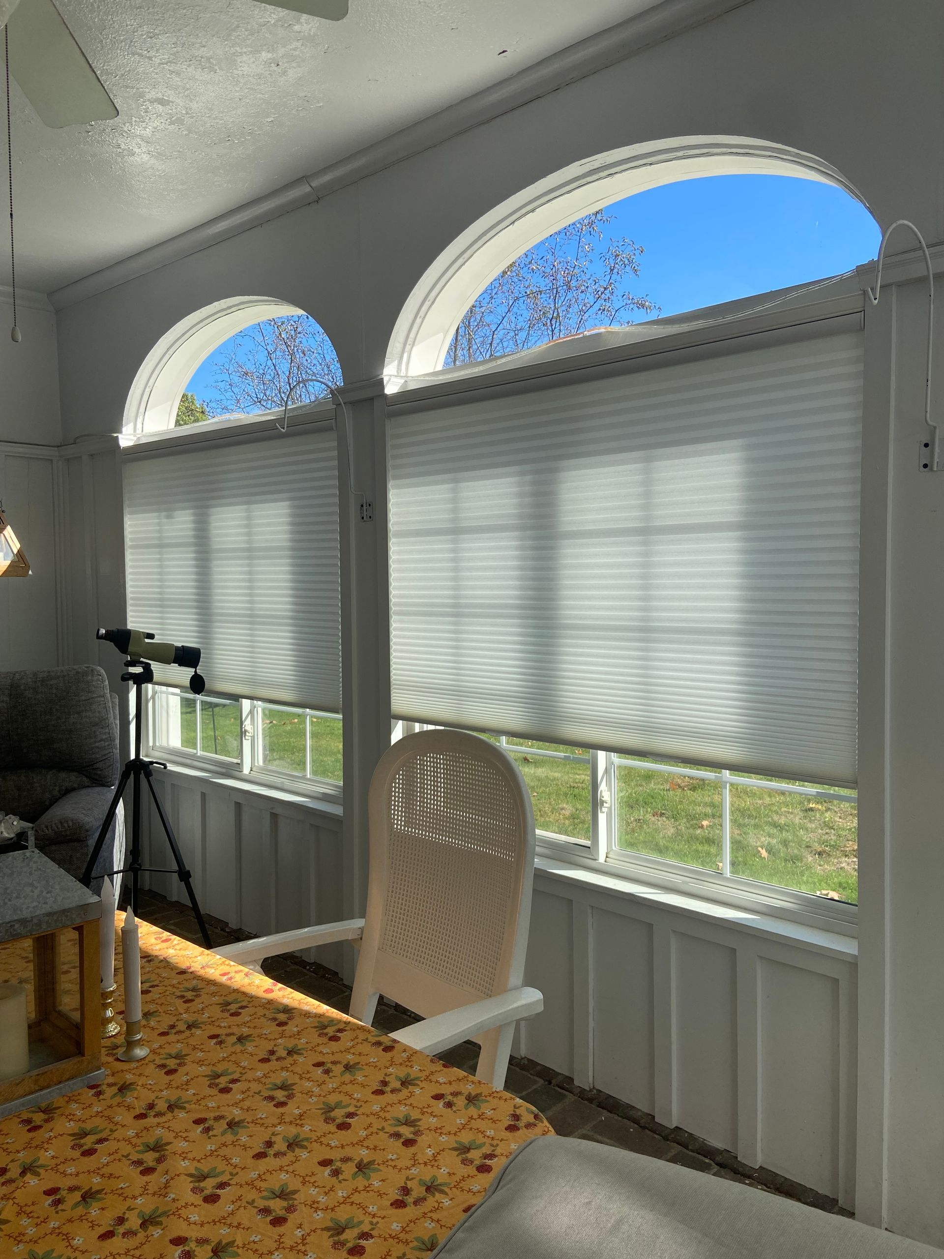 A sun room with a table , chairs , and a telescope.