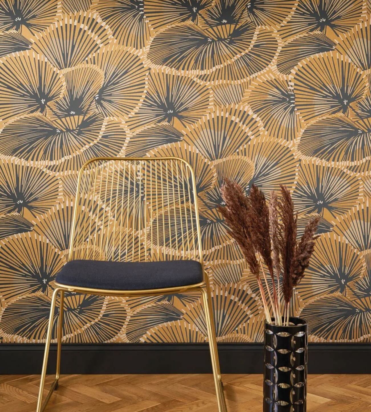 A chair is sitting in front of a wall with a vase of flowers.