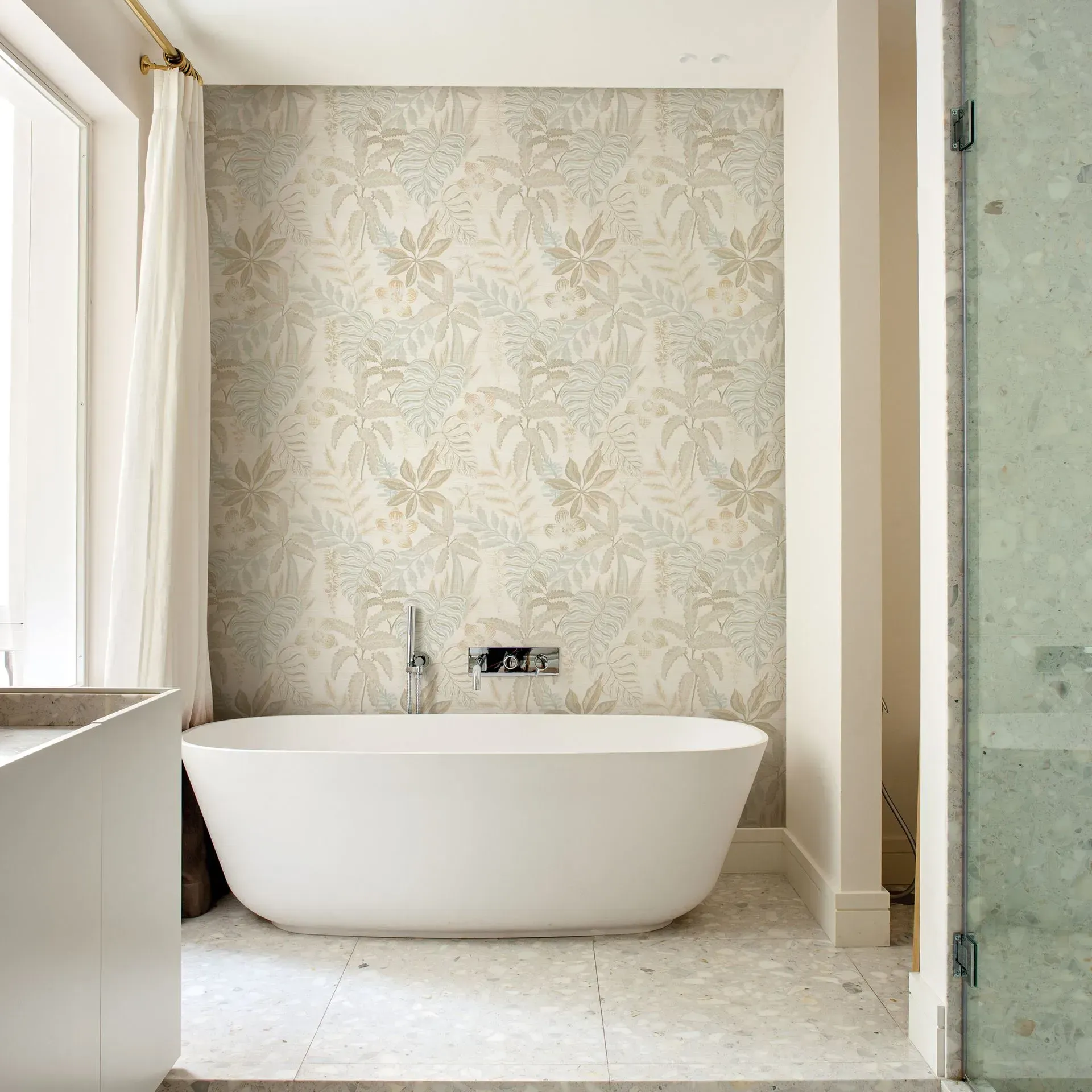 A bathtub in a bathroom with a floral wallpaper on the wall