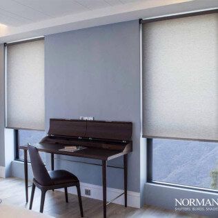 There is a desk and chair in the room with blinds on the windows.