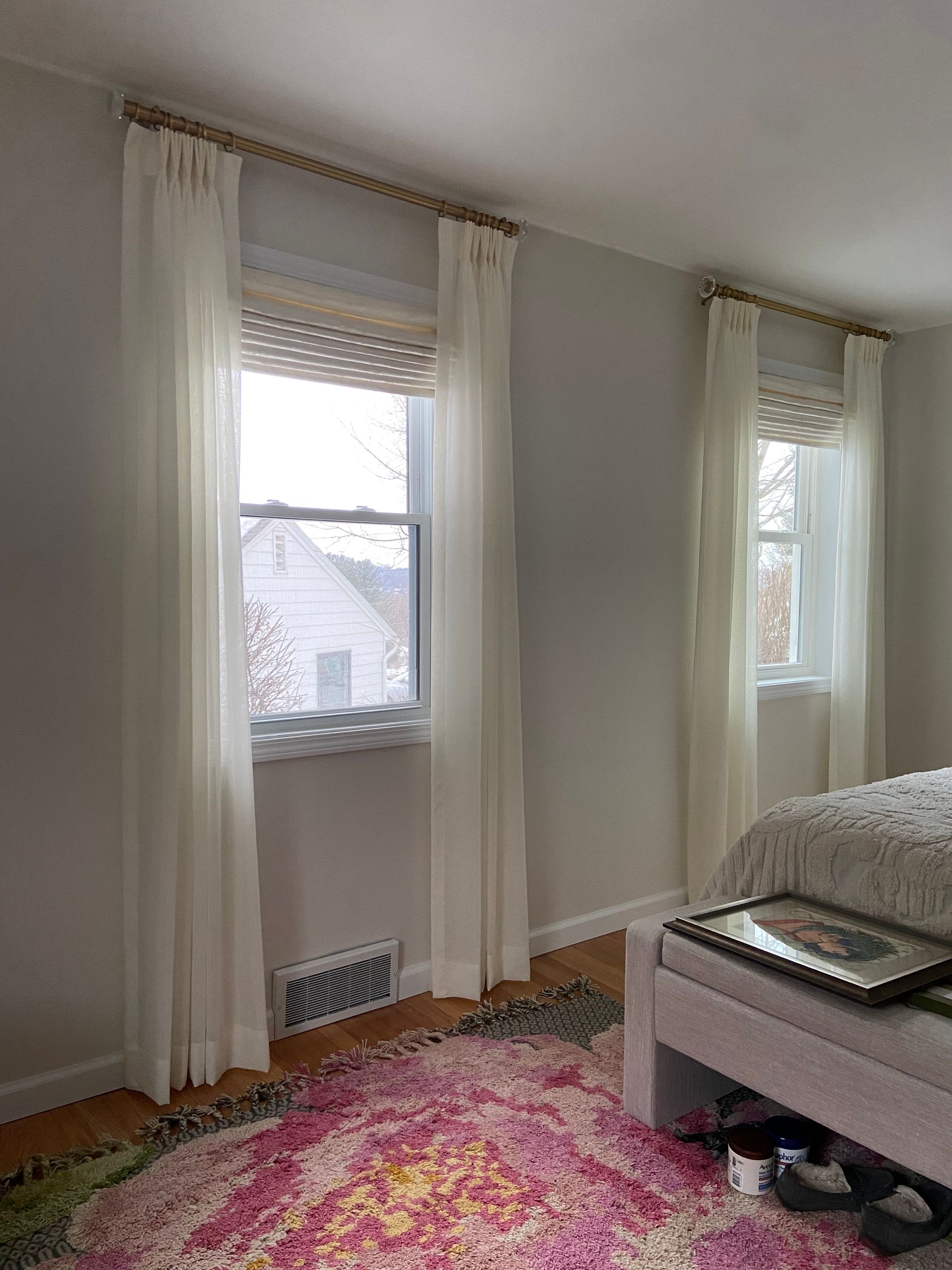 A bedroom with a bed , window , rug and curtains.