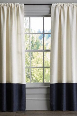 A pair of white and black curtains are hanging on a window.