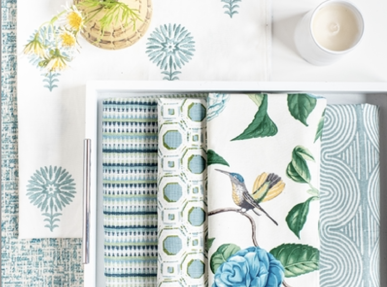 A white tray with blue and white towels and a cup on it