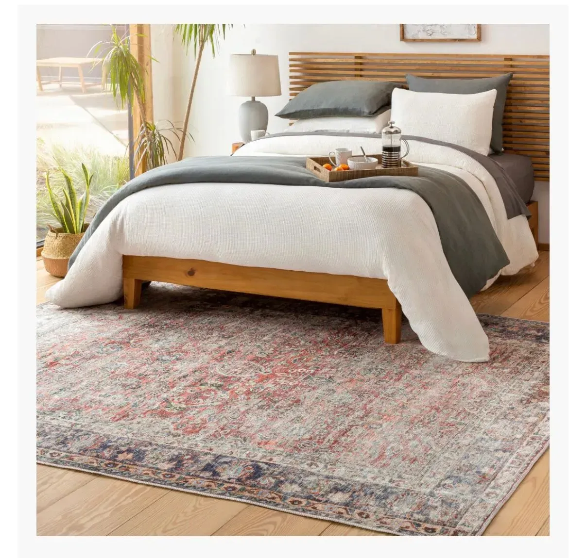 A bedroom with a bed and a rug on the floor