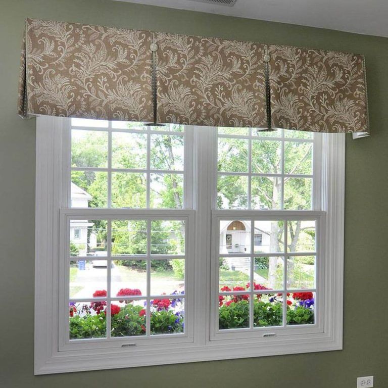 A window with a valance and flowers in the window sill