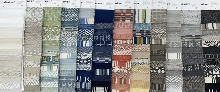 A bunch of different colored fabrics are lined up on a table.