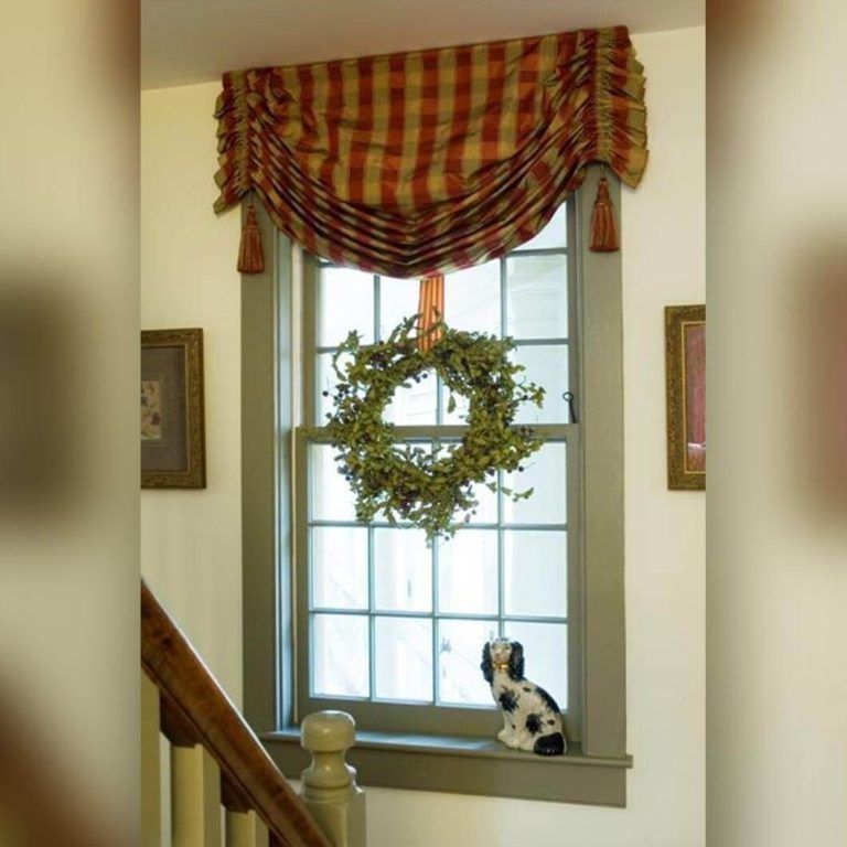 A dog is sitting on a window sill next to a window with a wreath on it