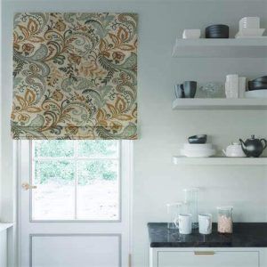 A kitchen with a window , shelves , and a floral roman shade.