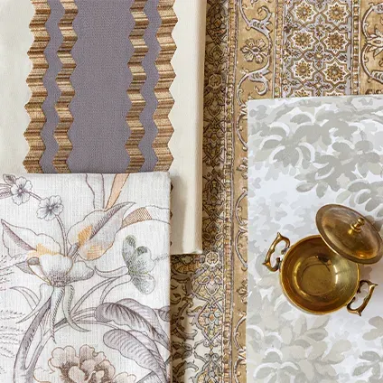A brass pot is sitting on a table next to a table cloth and a rug.