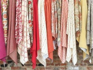 A bunch of blankets are hanging on a brick wall.