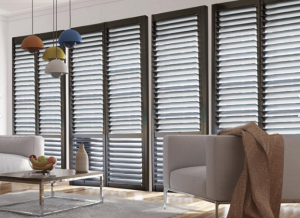 A living room with a couch , chair , coffee table and shutters on the windows