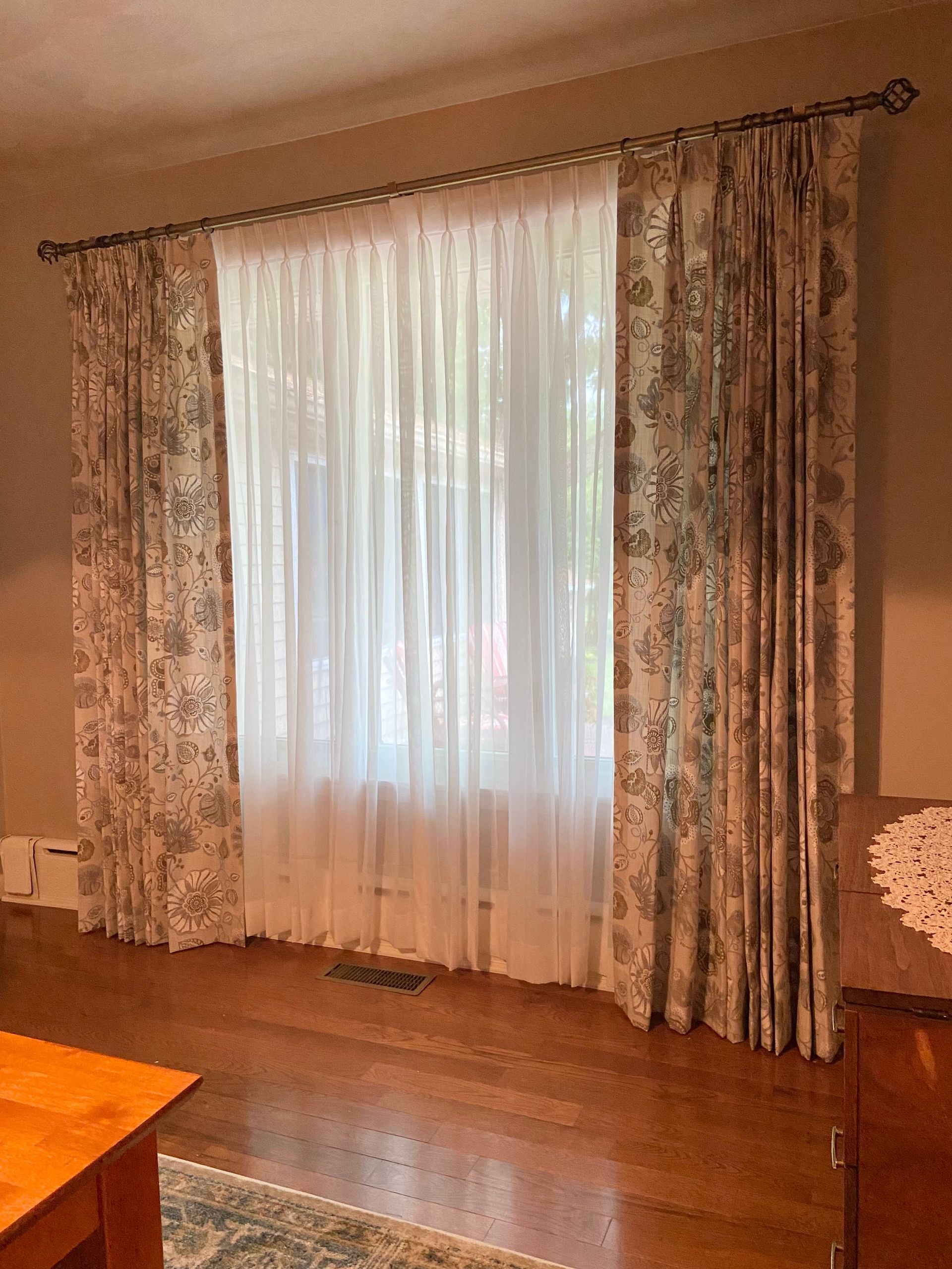 A living room with a large window and white curtains.