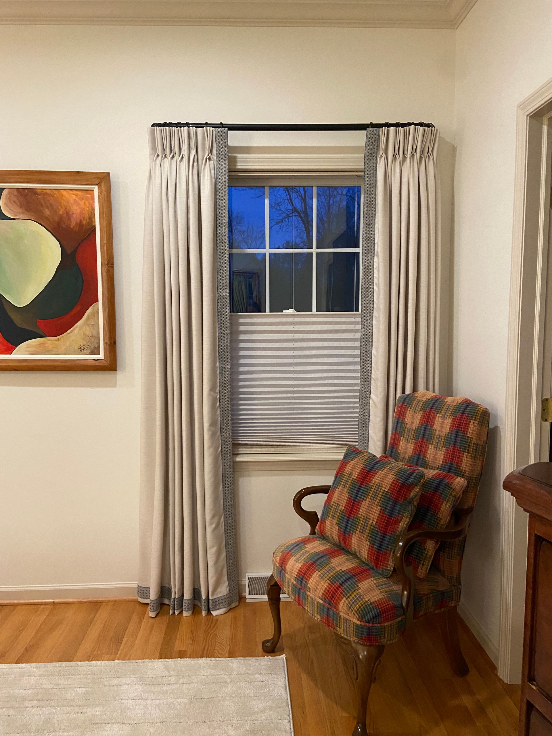 A living room with a chair and a window with curtains.