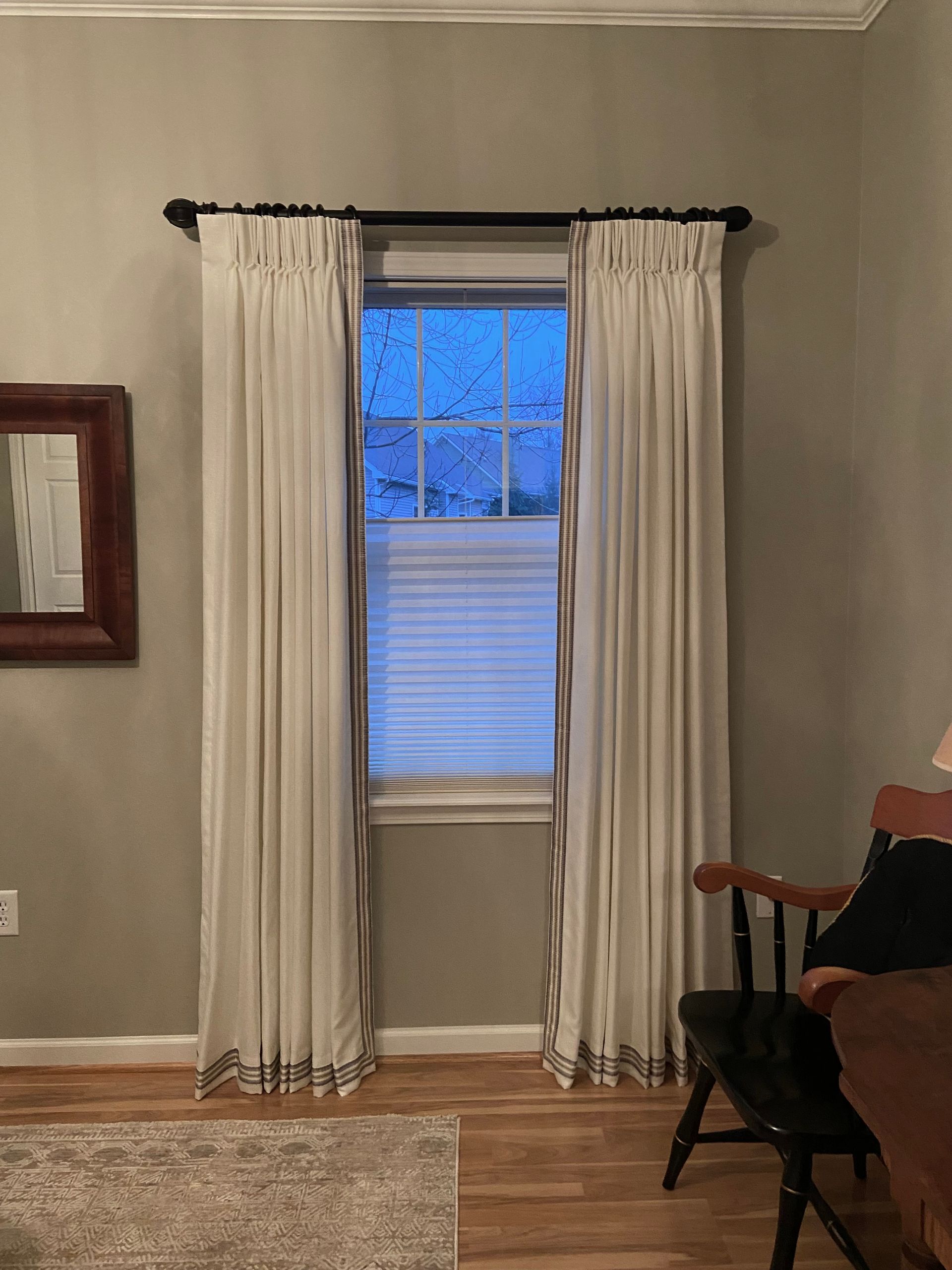 A living room with a chair and a window with white curtains.
