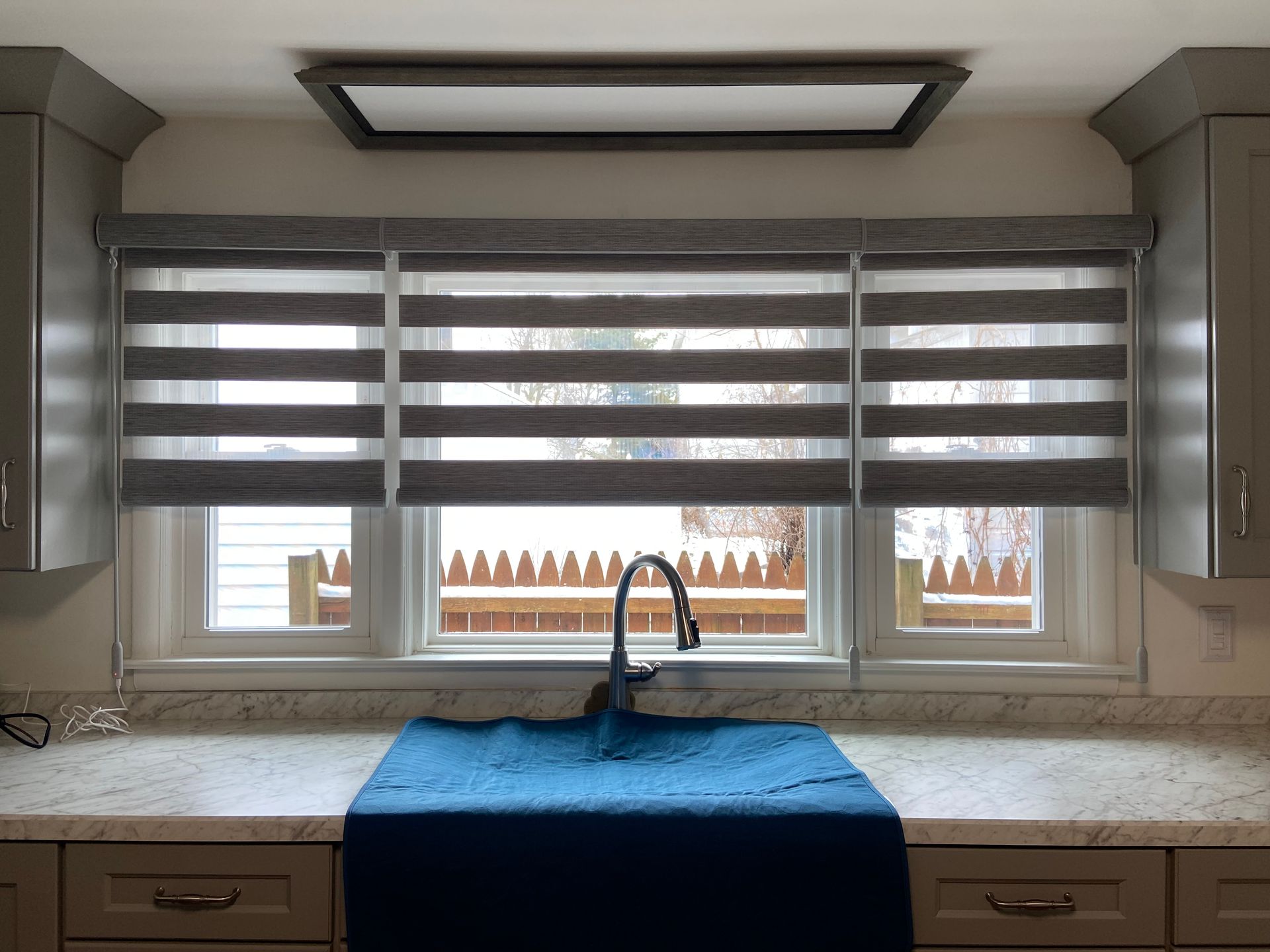 A kitchen with a sink and a window with blinds.