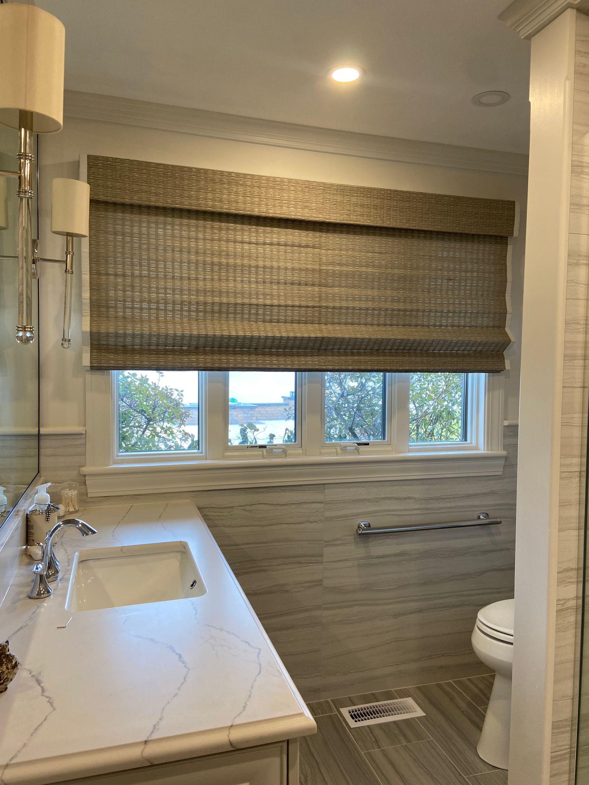 A bathroom with a sink , toilet and window.