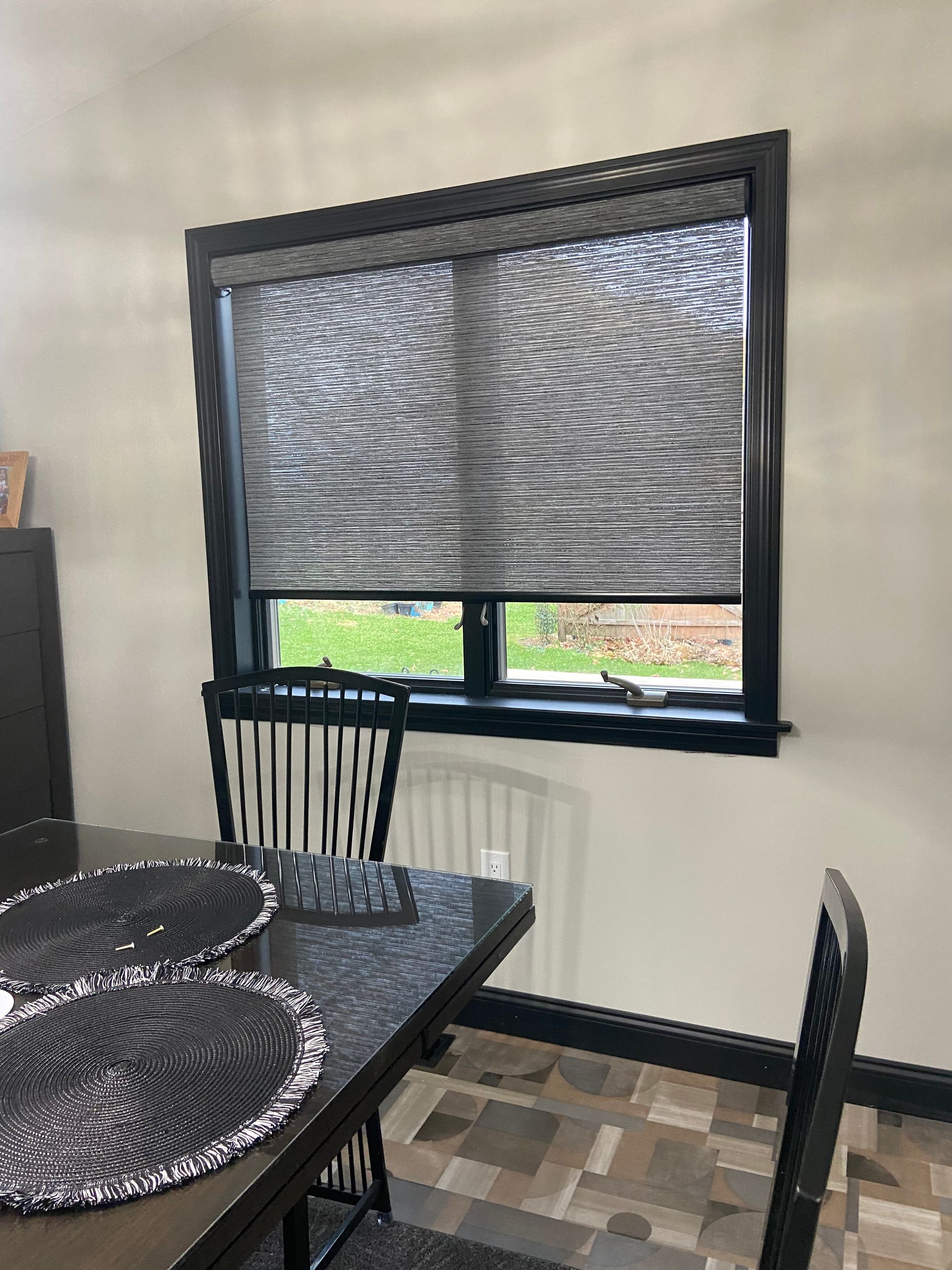 A dining room with a table and chairs and a window with blinds.